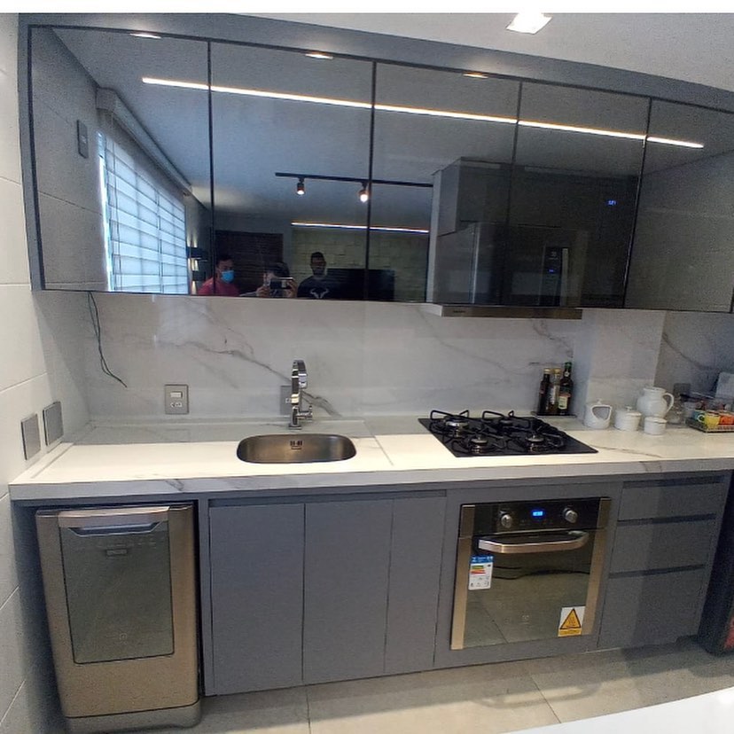 Cozinha planejada em cinza com armários superiores de vidro e revestimento de mármore